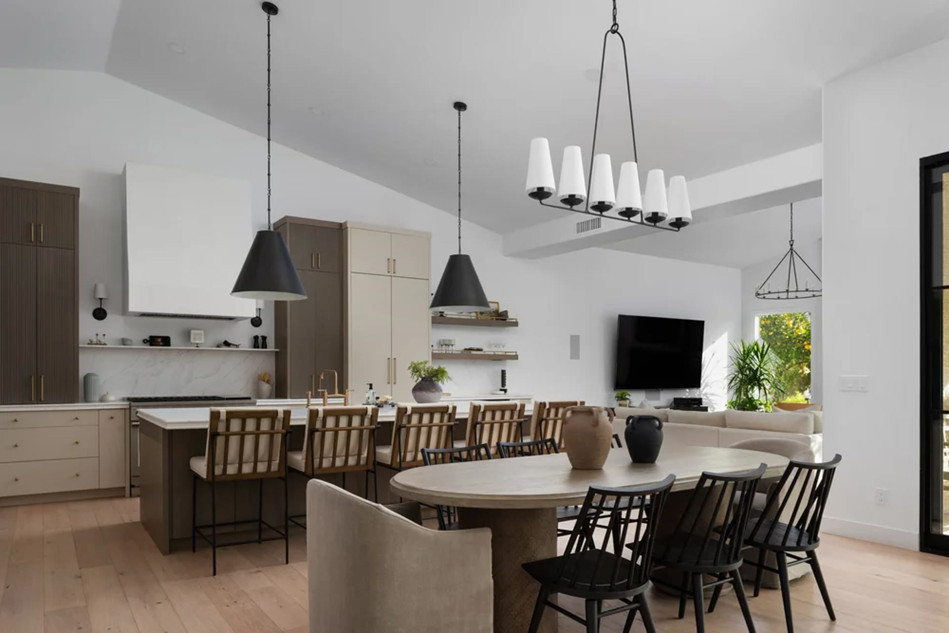 Kitchen, dining, and living held as one room — oak, black chairs, and a steel grid door to the garden. Across the Room, Paradise Valley, Desert Dwelling.