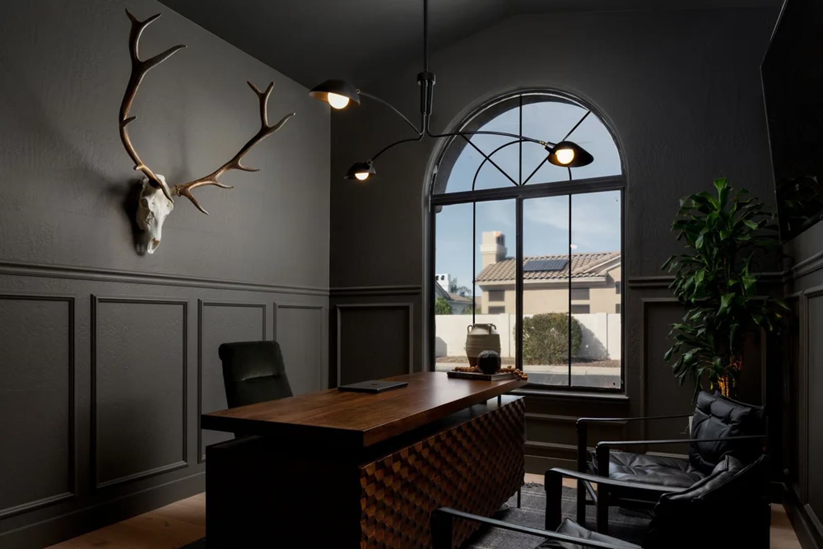 The study — dark paneling, an arched steel window, and a walnut desk. Across the Room, Paradise Valley, Desert Dwelling.