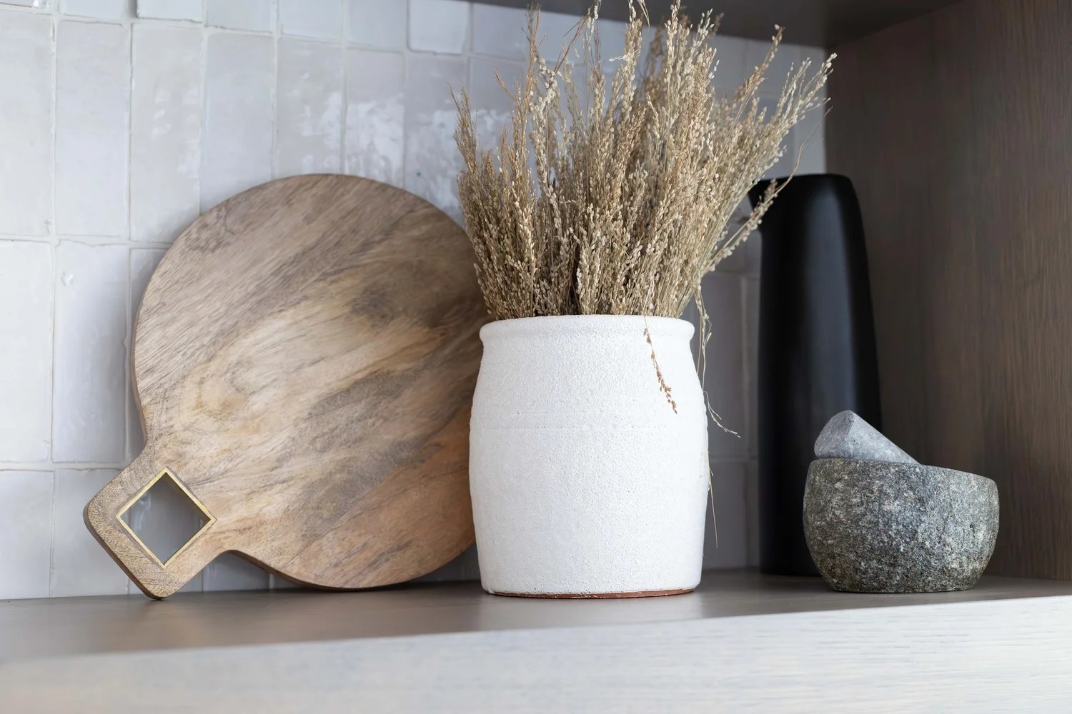 Open oak shelving with a cutting board, dried grass, and stone. Devotion, Ancala, Desert Dwelling.