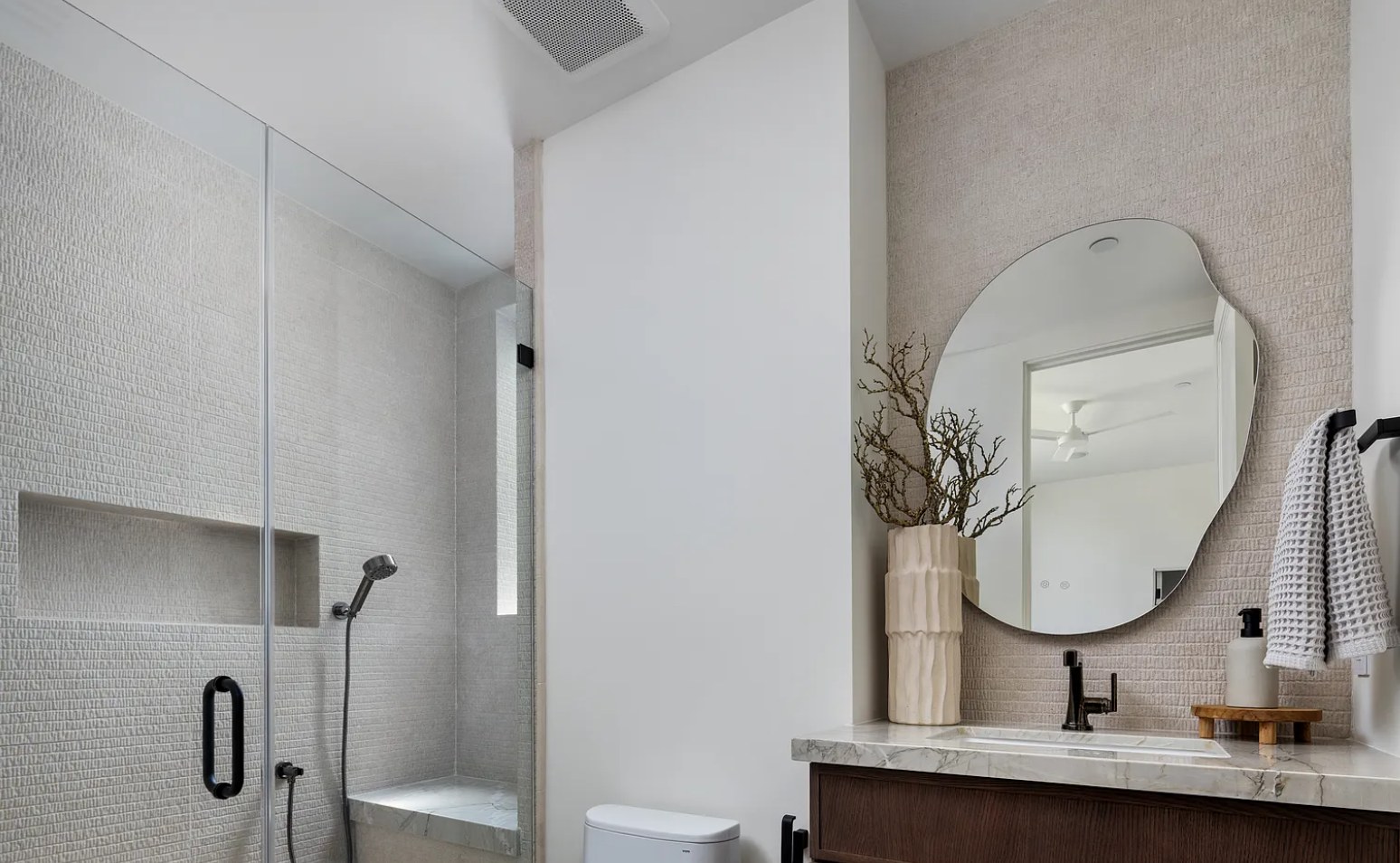 A guest bath with an organic mirror, marble, and a textured tile shower. I, Run, Paradise Valley, Desert Dwelling.