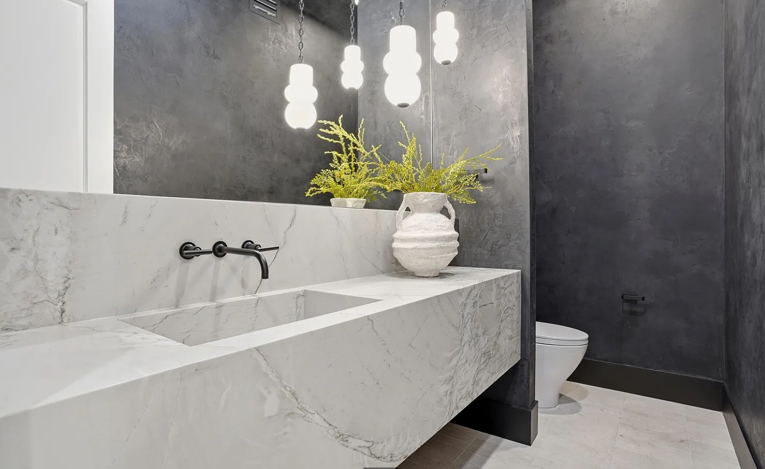 Powder room with a marble trough sink, black fittings, and a dark plaster wall. I, Run, Paradise Valley, Desert Dwelling.