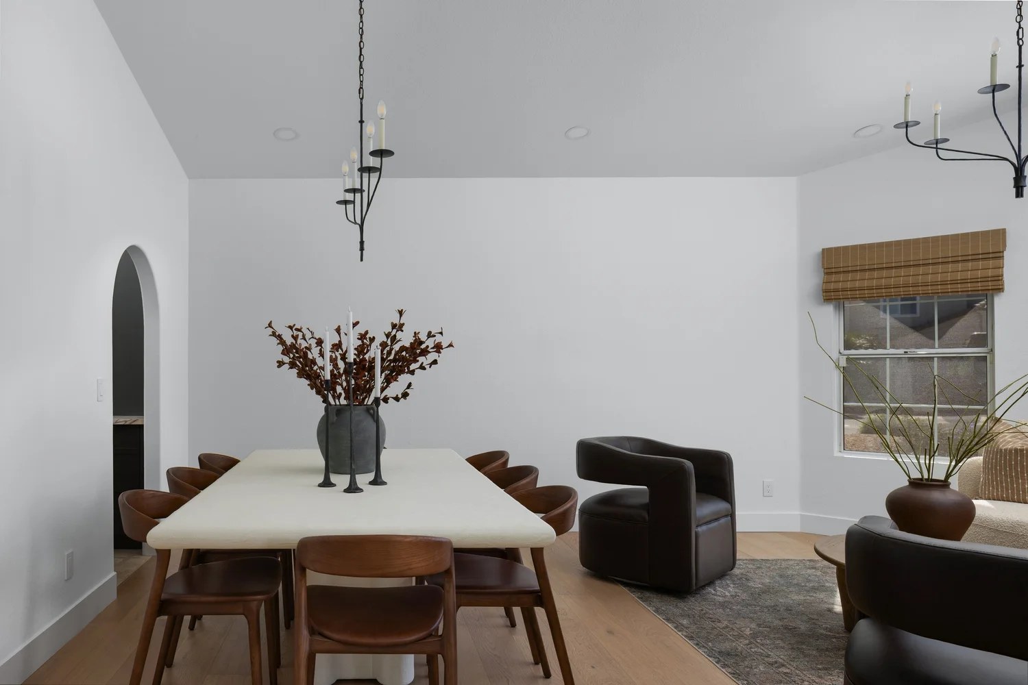 Dining under iron candle chandeliers, a cream table, and a dark swivel chair. New Beginnings, Scottsdale, Desert Dwelling.