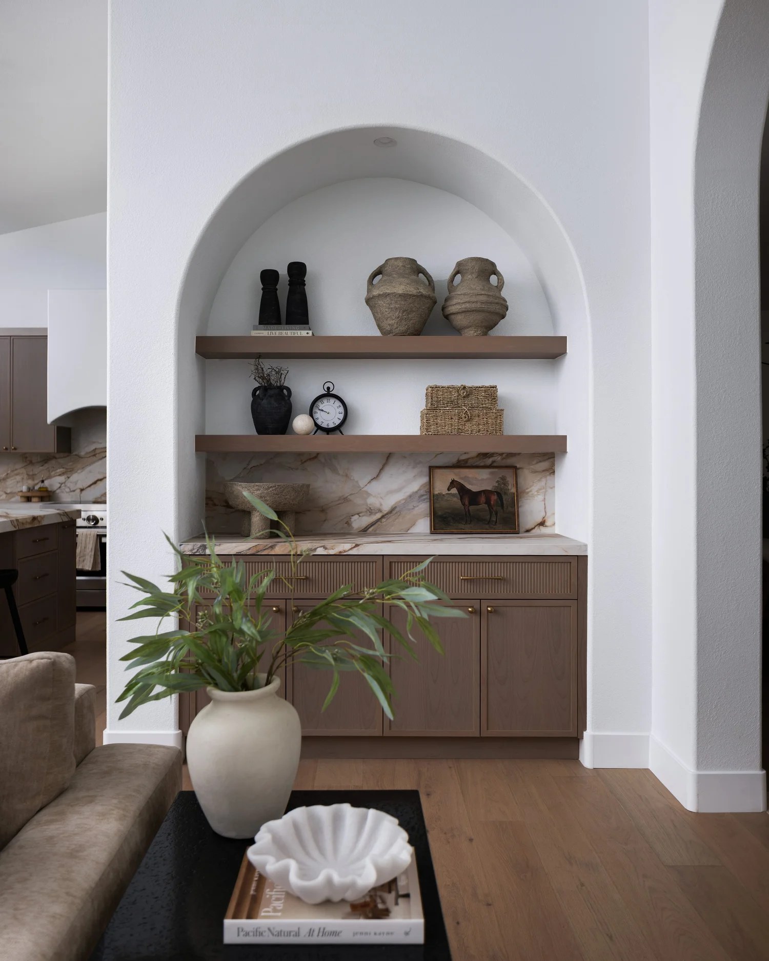 An arched plaster niche with oak shelves, marble, and a horse painting. New Beginnings, Scottsdale, Desert Dwelling.