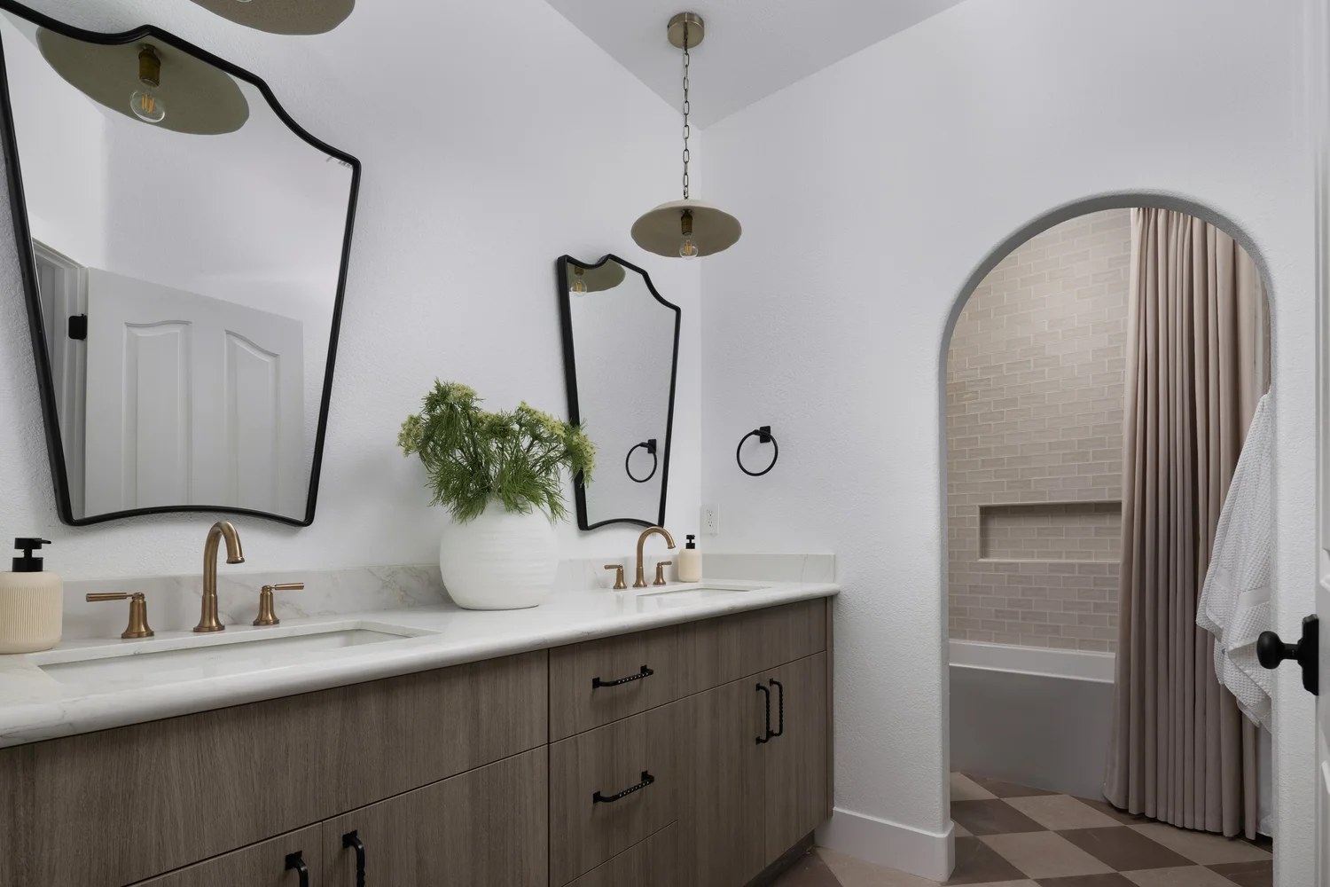 A dual oak vanity with marble, bronze faucets, and tall black-framed mirrors. New Beginnings, Scottsdale, Desert Dwelling.