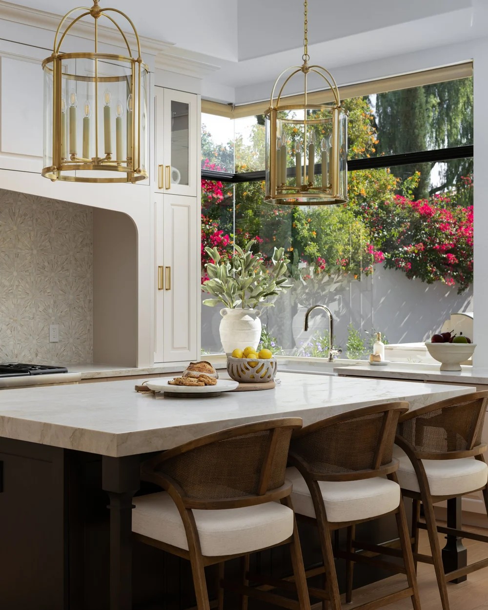 The kitchen island with cane stools, brass lanterns, and bougainvillea beyond the corner window. Tuckey, Scottsdale, Desert Dwelling.