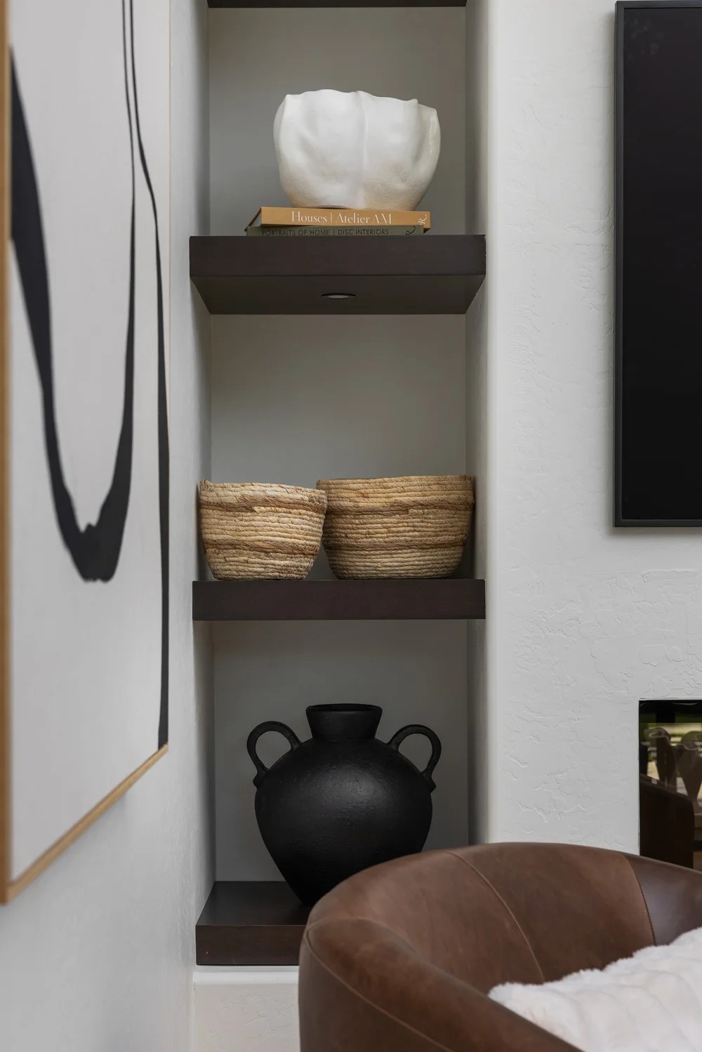 A plaster niche with dark shelves, woven baskets, and a black vessel. Tuckey, Scottsdale, Desert Dwelling.